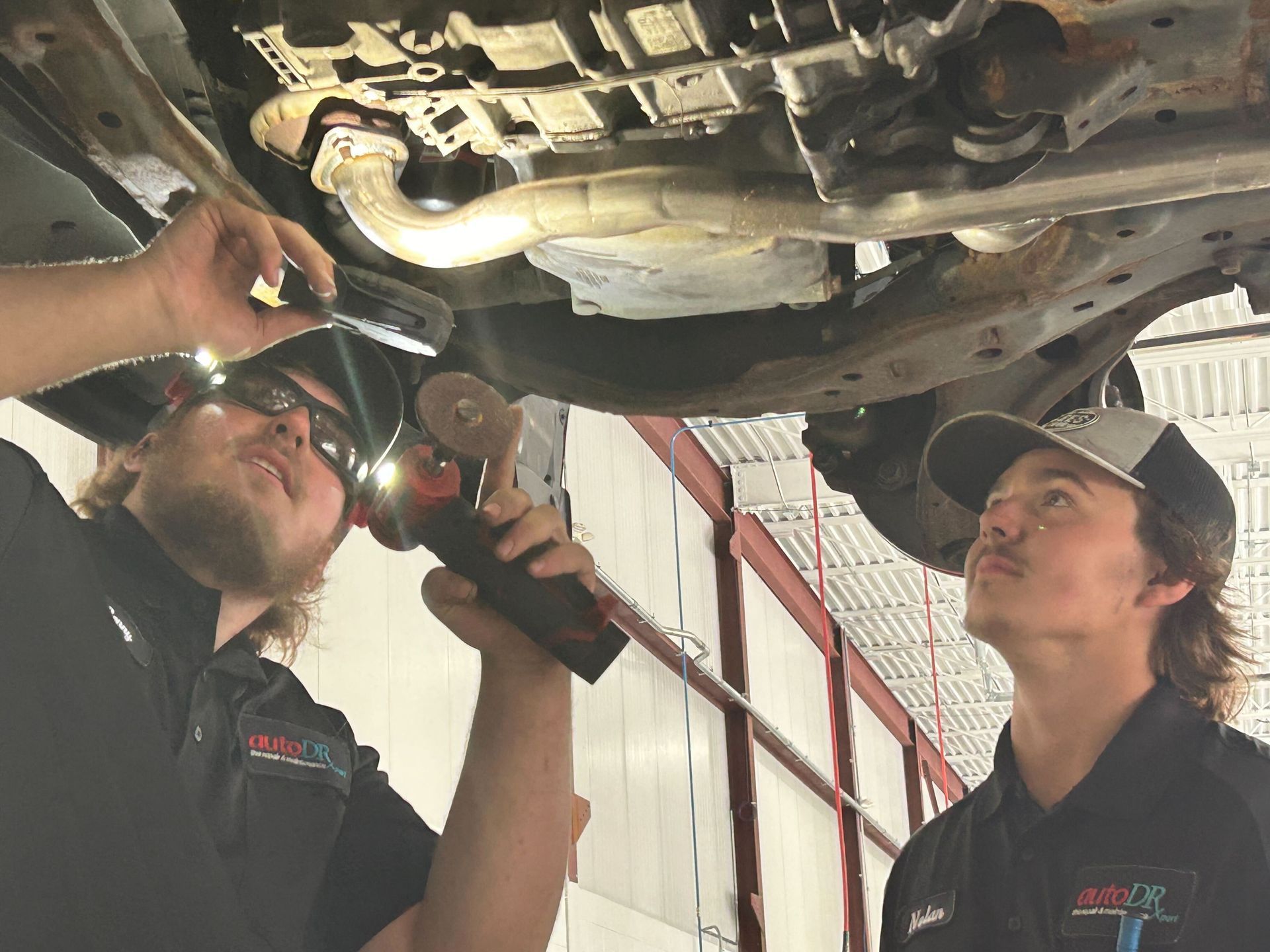 Two Technicians Inspecting Undercarriage Components On Vehicle Lift | Auto DR