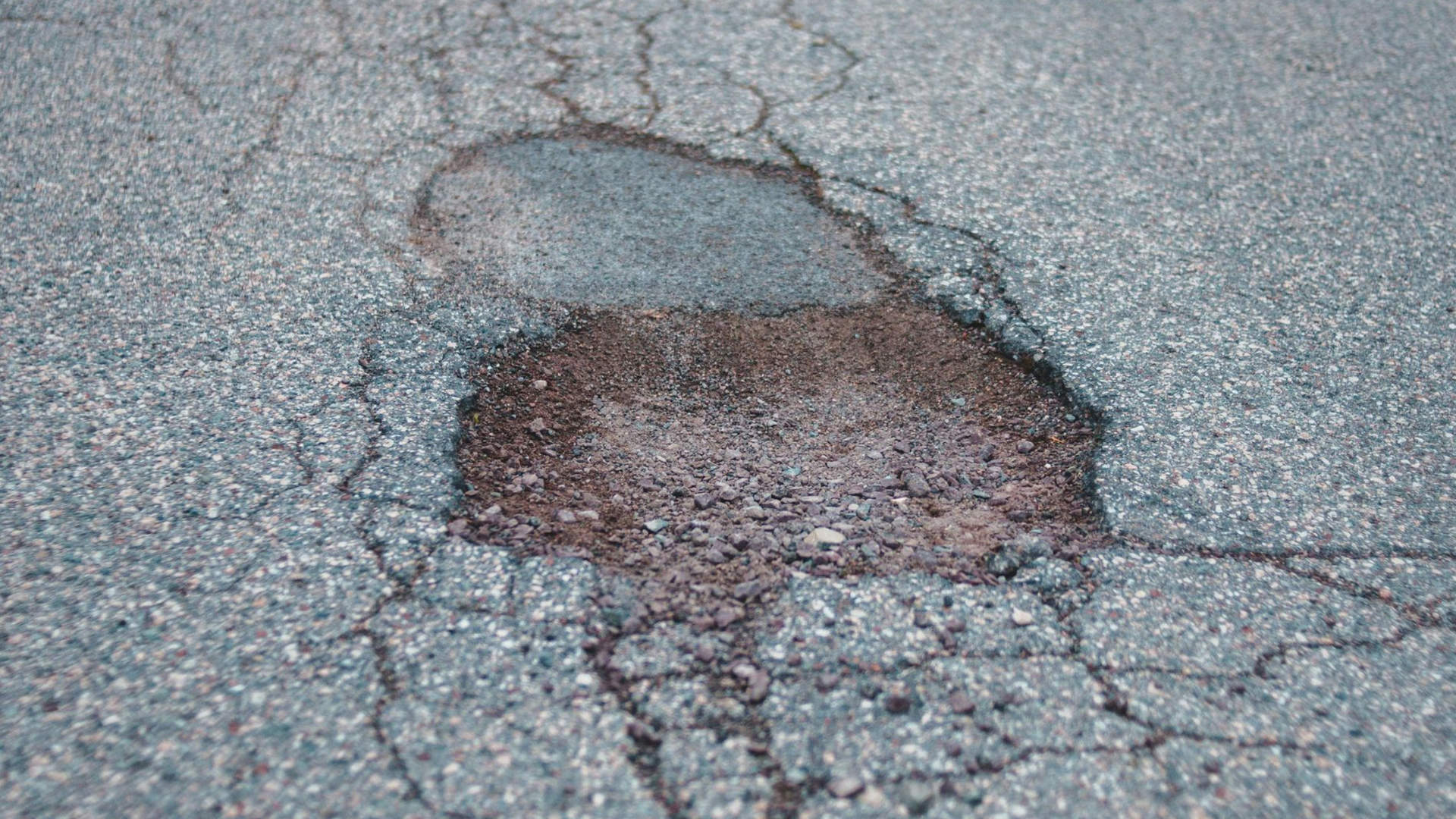 A car has a flat tire after hitting a pothole driving on during on a Michigan road.