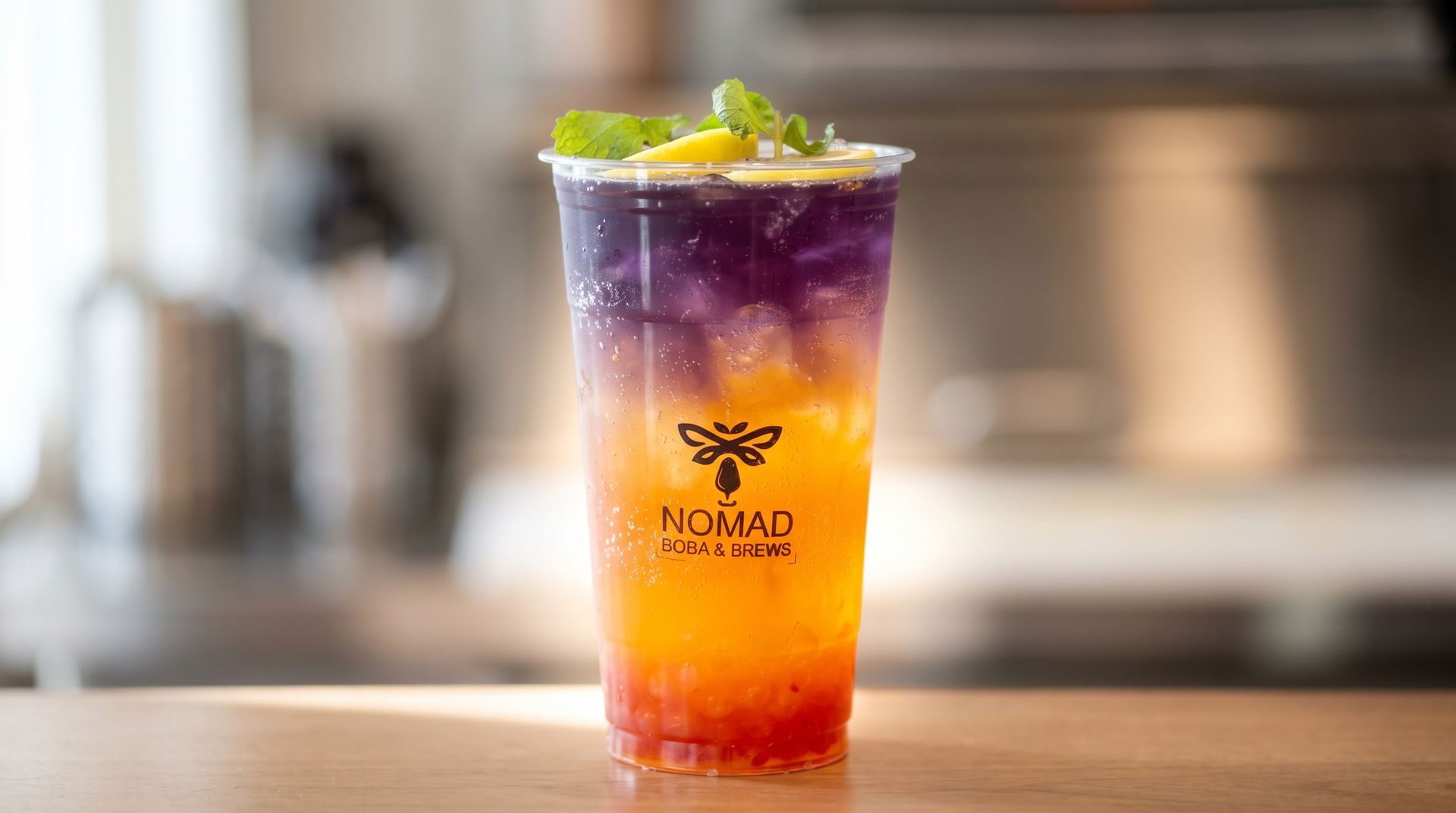 Colorful layered iced drink in a clear cup with lime garnish on a wooden counter