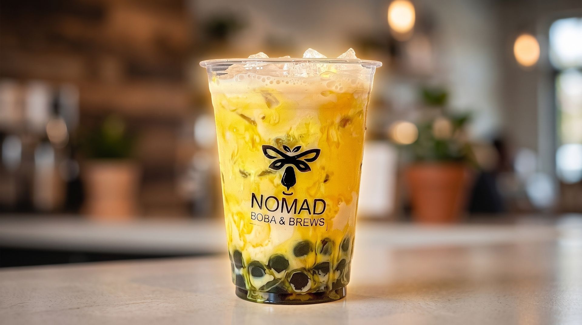 Iced bubble tea in a clear cup with black tapioca pearls on a café counter.