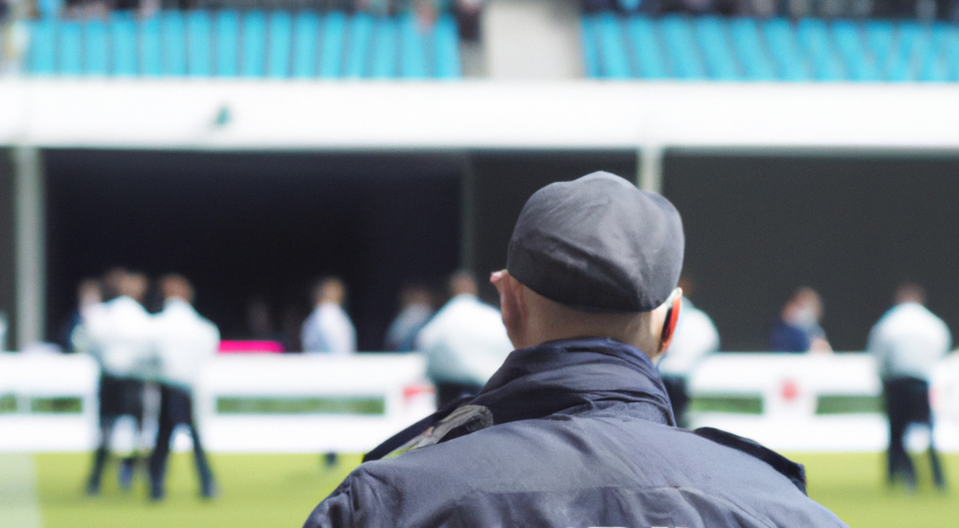 A man in a hat is standing in front of a soccer field.