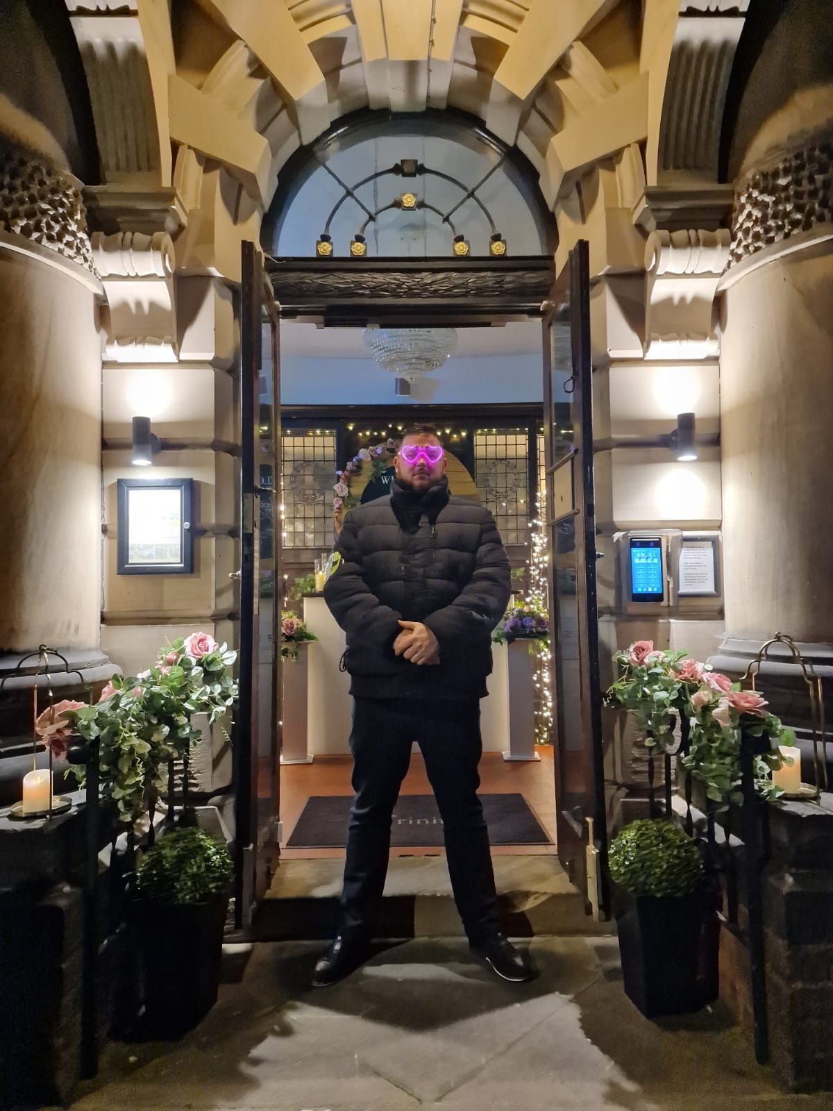 A man in a black jacket is standing in front of a building