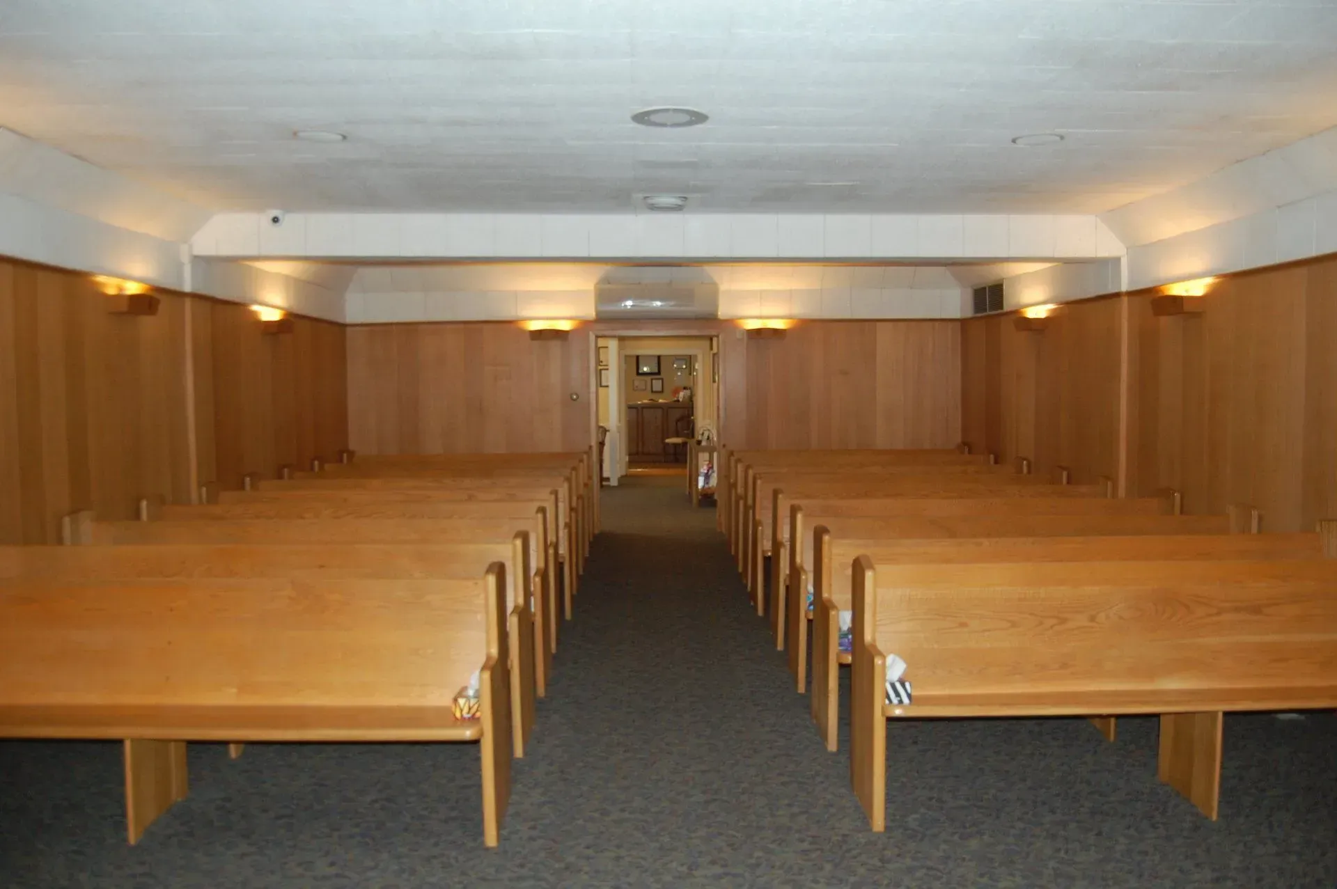 Empty church pews facing a central aisle in a wood-paneled room