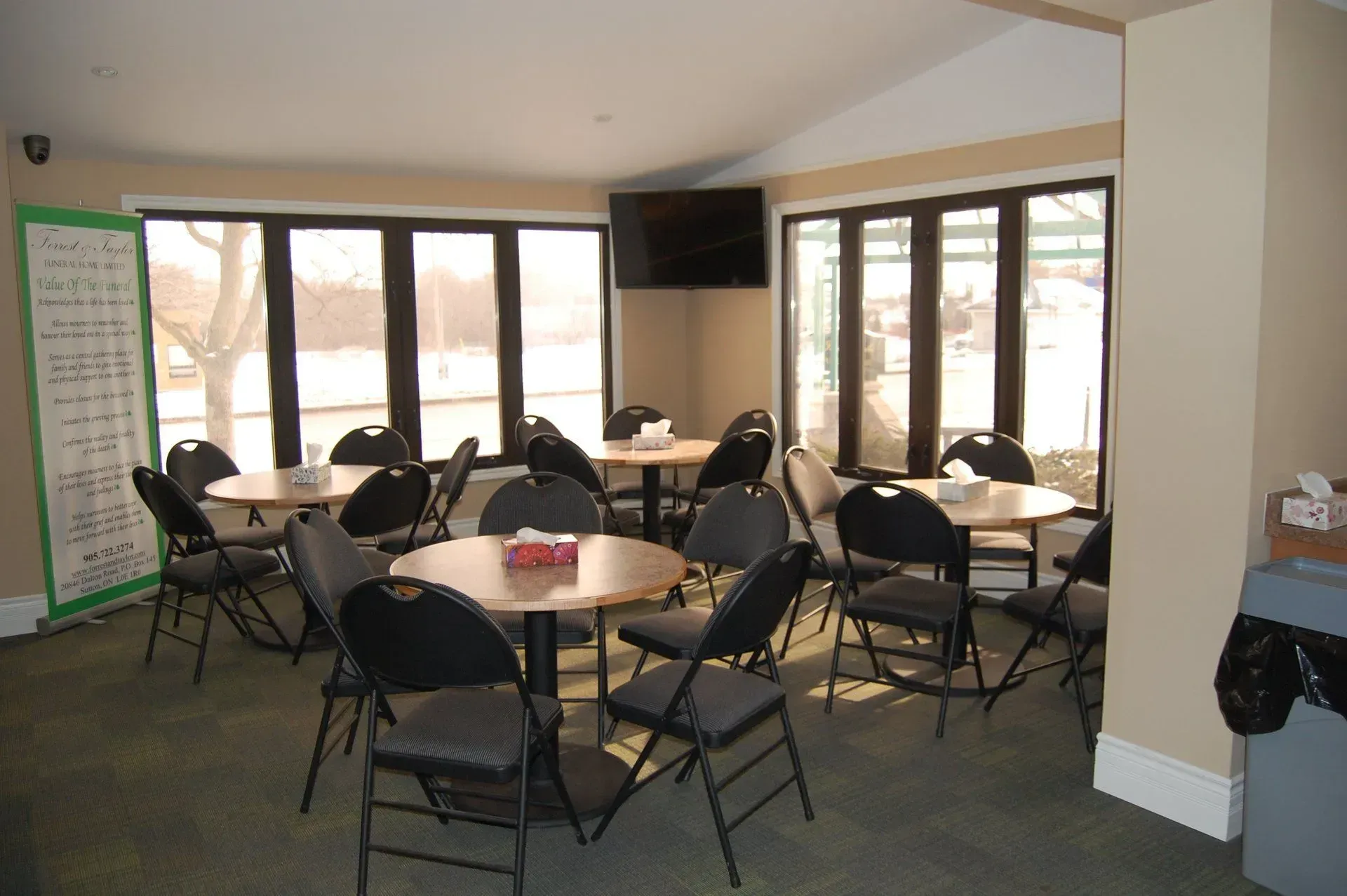 Empty conference room with round tables, black folding chairs, and large windows.