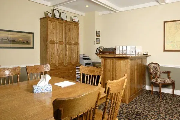 Office waiting room with wooden table, chairs, cabinet, and reception desk