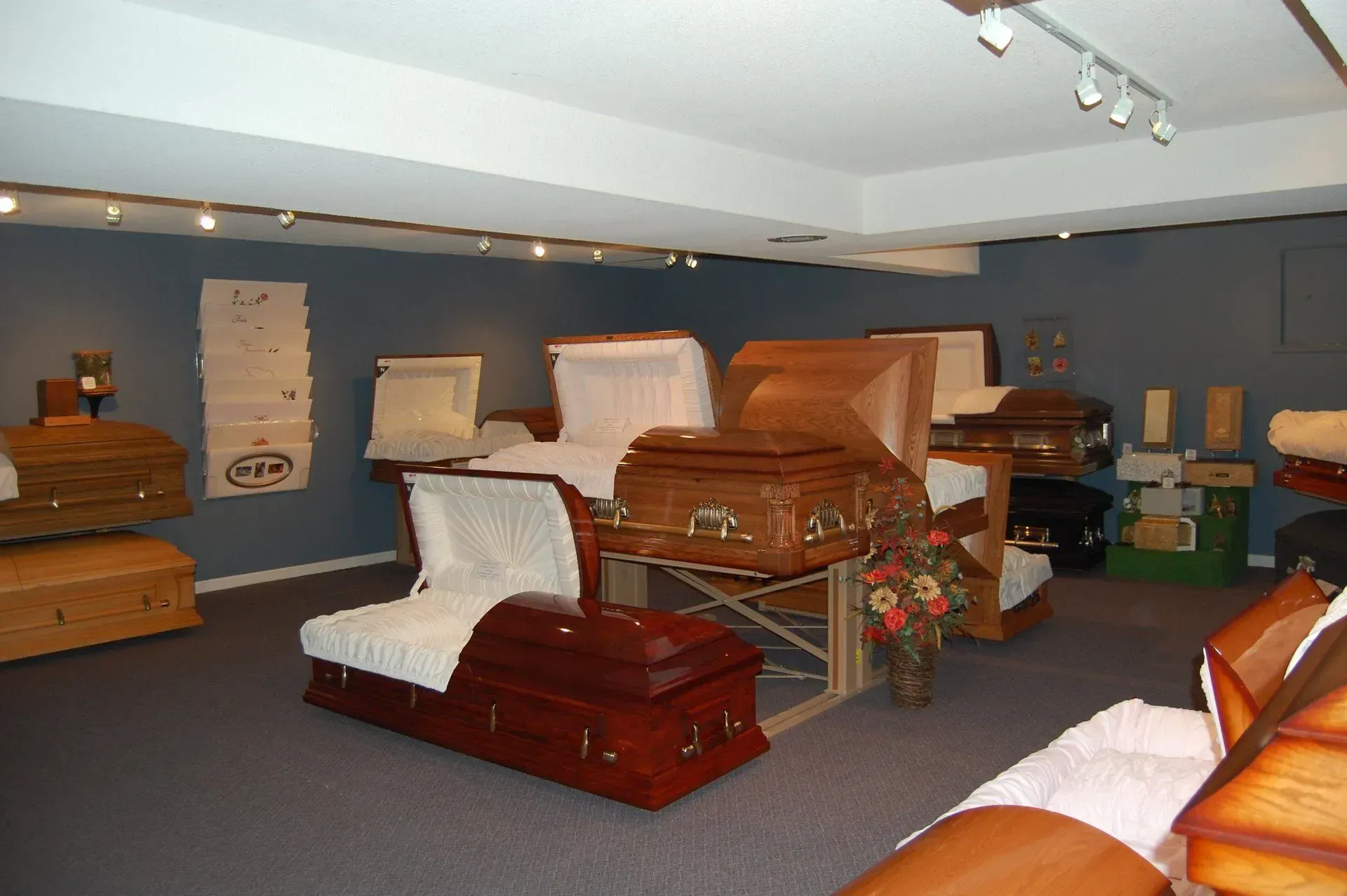 Furniture showroom with several wooden beds and couches displayed in a carpeted room