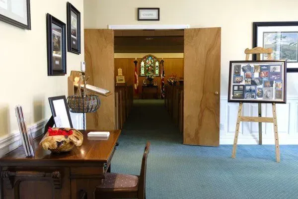 Office hallway with framed photos, a desk, and an easel display on a blue carpet