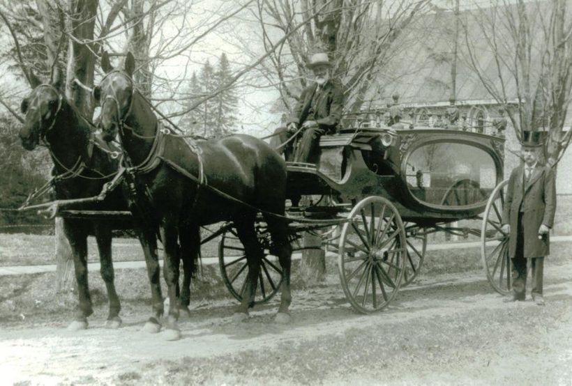 Horse-drawn carriage on a snowy street with a man standing beside it