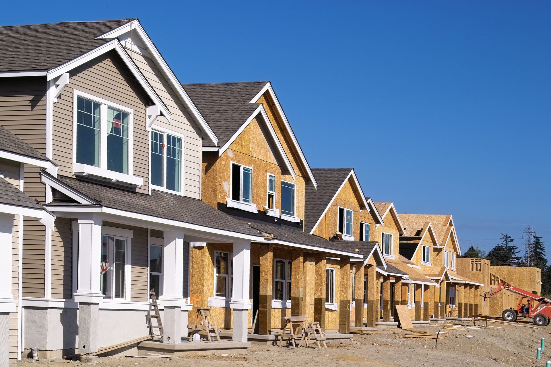 A row of houses under construction with a blue sky in the background