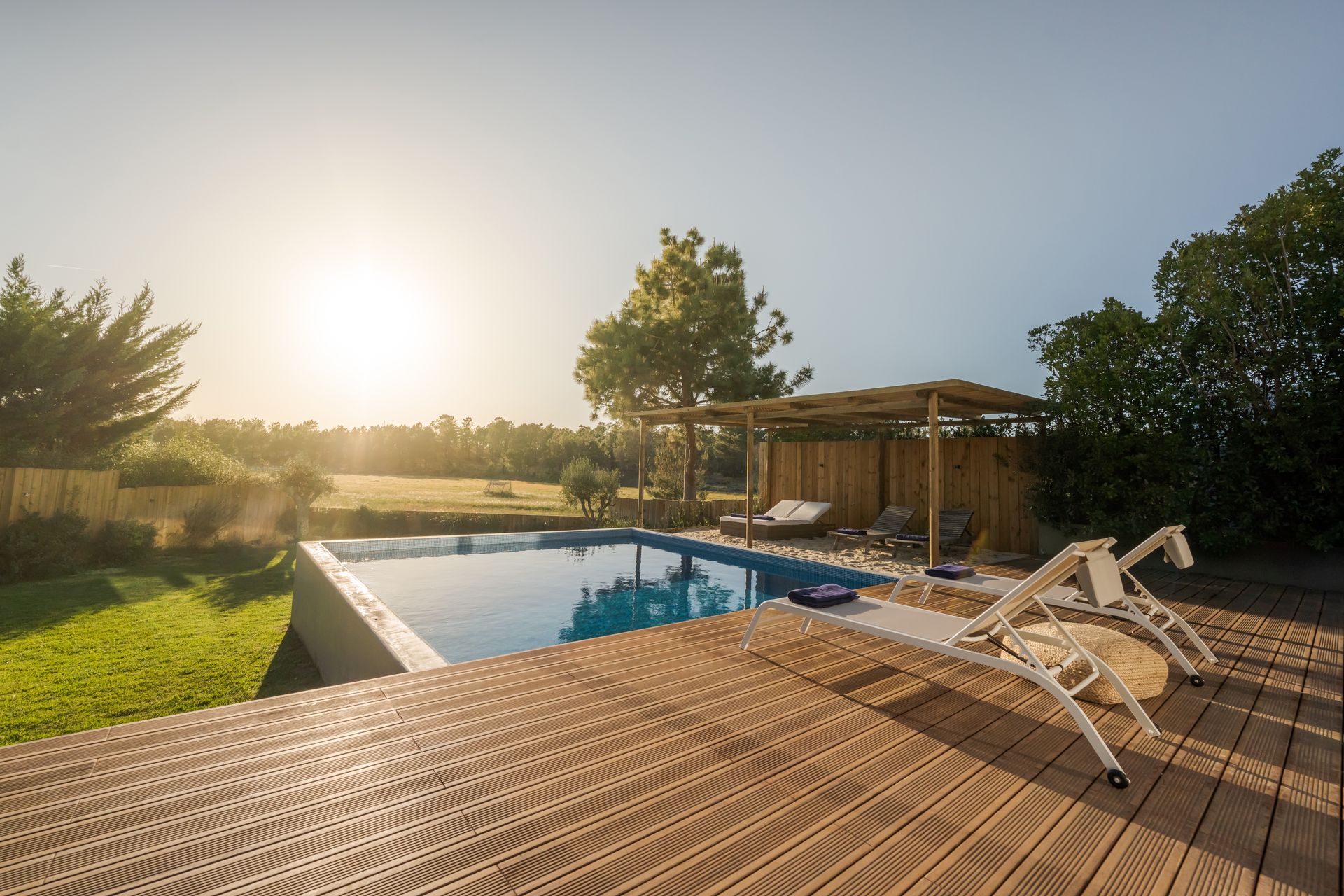 Composite deck surrounding a backyard pool with outdoor seating and privacy fencing in a Missouri re
