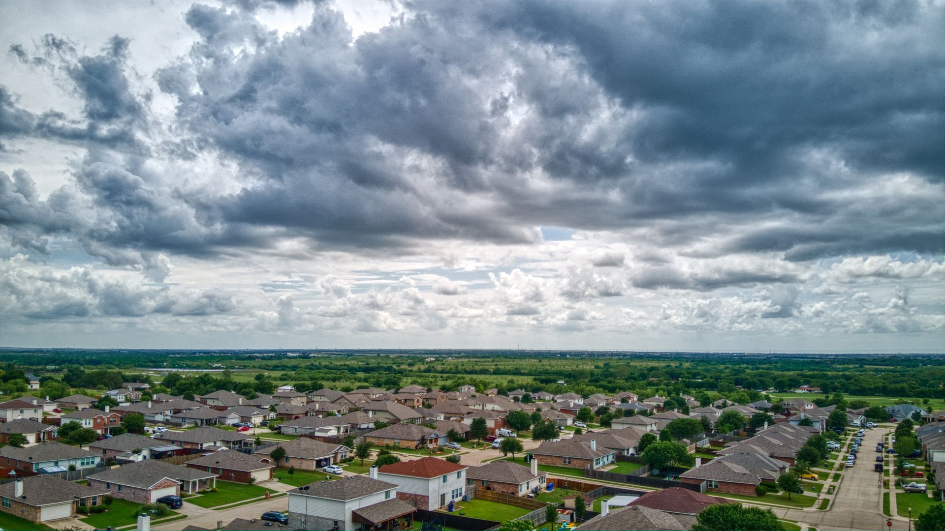 Storm clouds over Missouri neighborhood with residential fencing and backyards visible from above
