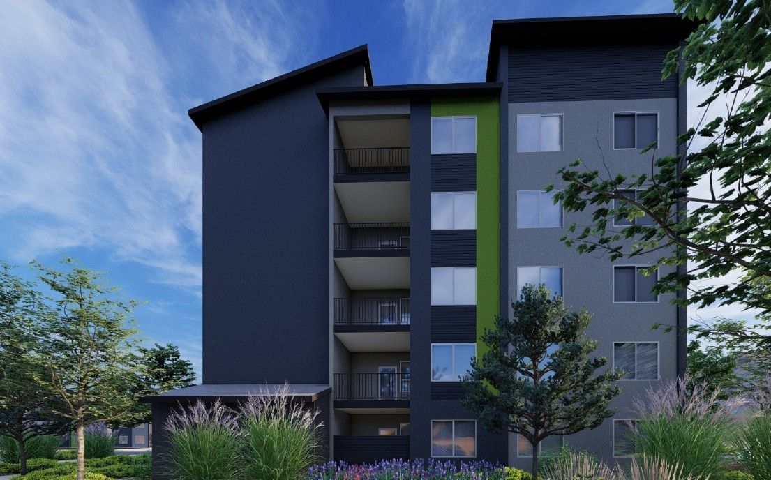 Modern apartment building with dark gray walls, balconies, and greenery outside
