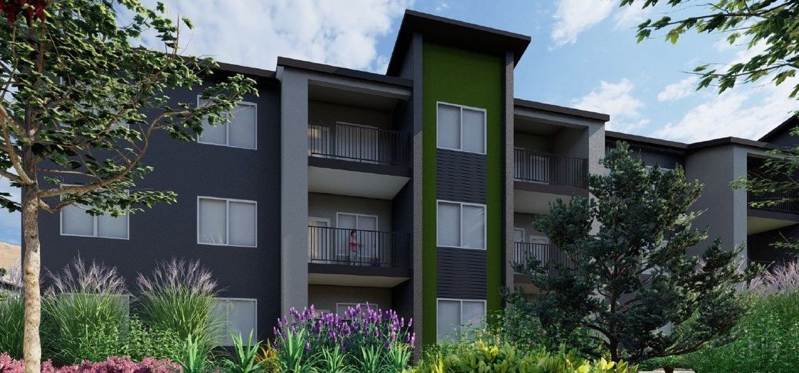 Modern apartment building with balconies, dark gray facade, and lush landscaping