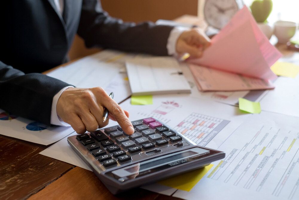 A Man Is Using A Calculator At A Desk — Visionary Accounting In Narromine, NSW