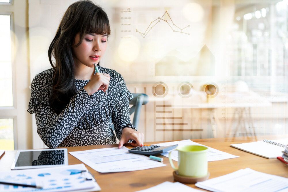 A Woman Is Sitting At A Table Using A Calculator And A Pen — Visionary Accounting In Narromine, NSW