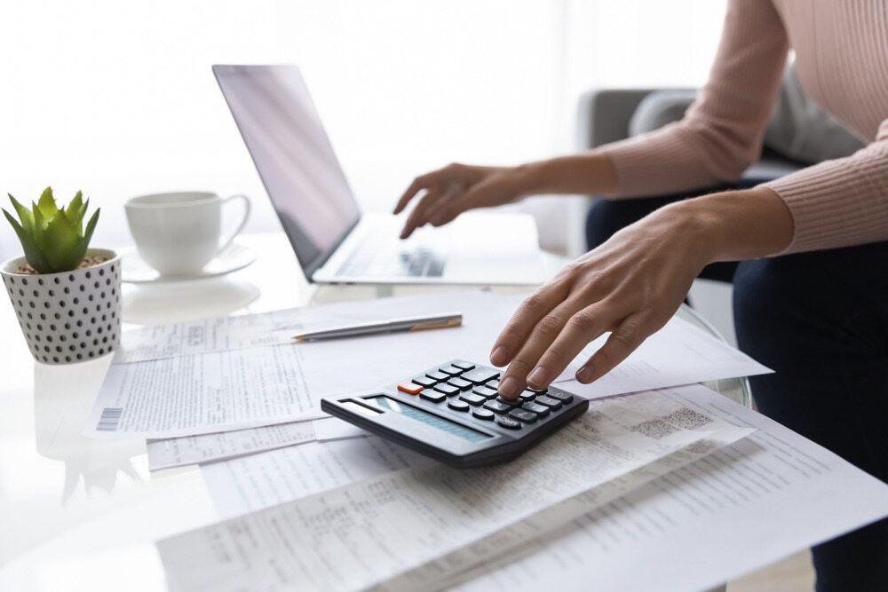 A Woman Is Using A Laptop And A Calculator At The Same Time — Visionary Accounting In Coonamble, NSW