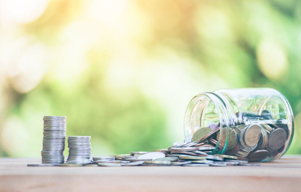 A Jar Filled With Coins Is Sitting On A Wooden Table Next To Stacks Of Coins — Visionary Accounting In Bourke, NSW