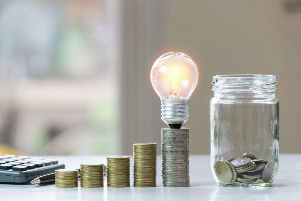 A Light Bulb Is Sitting On Top Of A Stack Of Coins Next To A Jar Of Coins — Visionary Accounting In Bourke, NSW