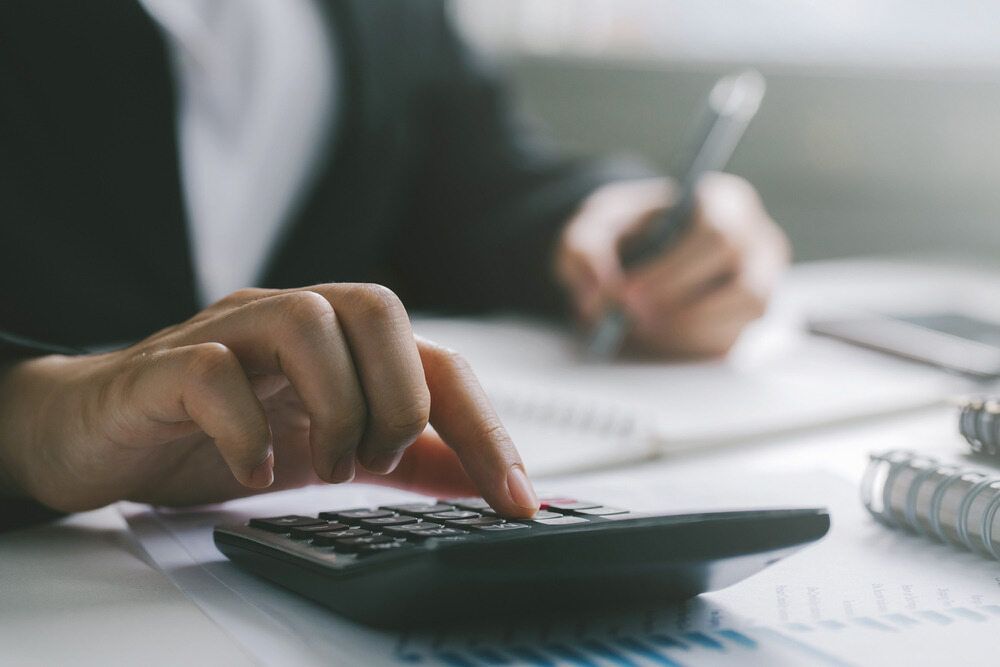 A Person Is Using A Calculator And Writing On A Piece Of Paper — Visionary Accounting In Coonamble, NSW