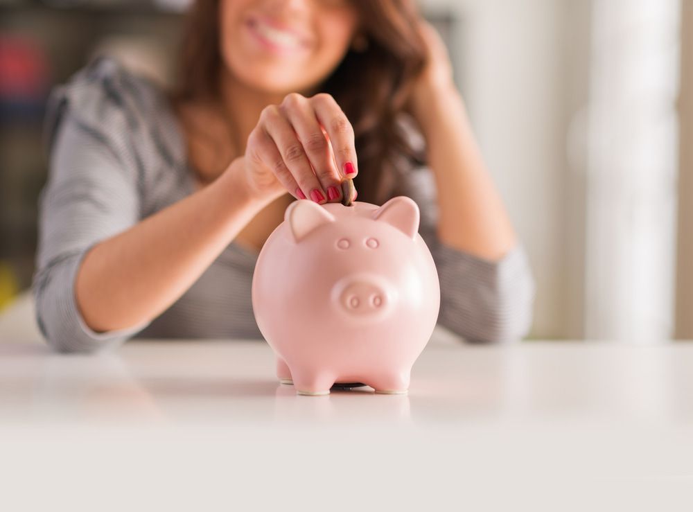 A Woman Is Putting A Coin Into A Pink Piggy Bank — Visionary Accounting In Wellington, NSW