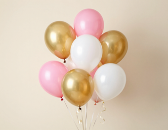 Globos rosas, blancos y dorados atados entre sí sobre un fondo beige.
