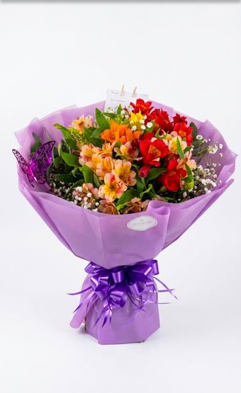 Ramo de rosas rosa pálido y flores blancas dispuestas en un jarrón de cristal.