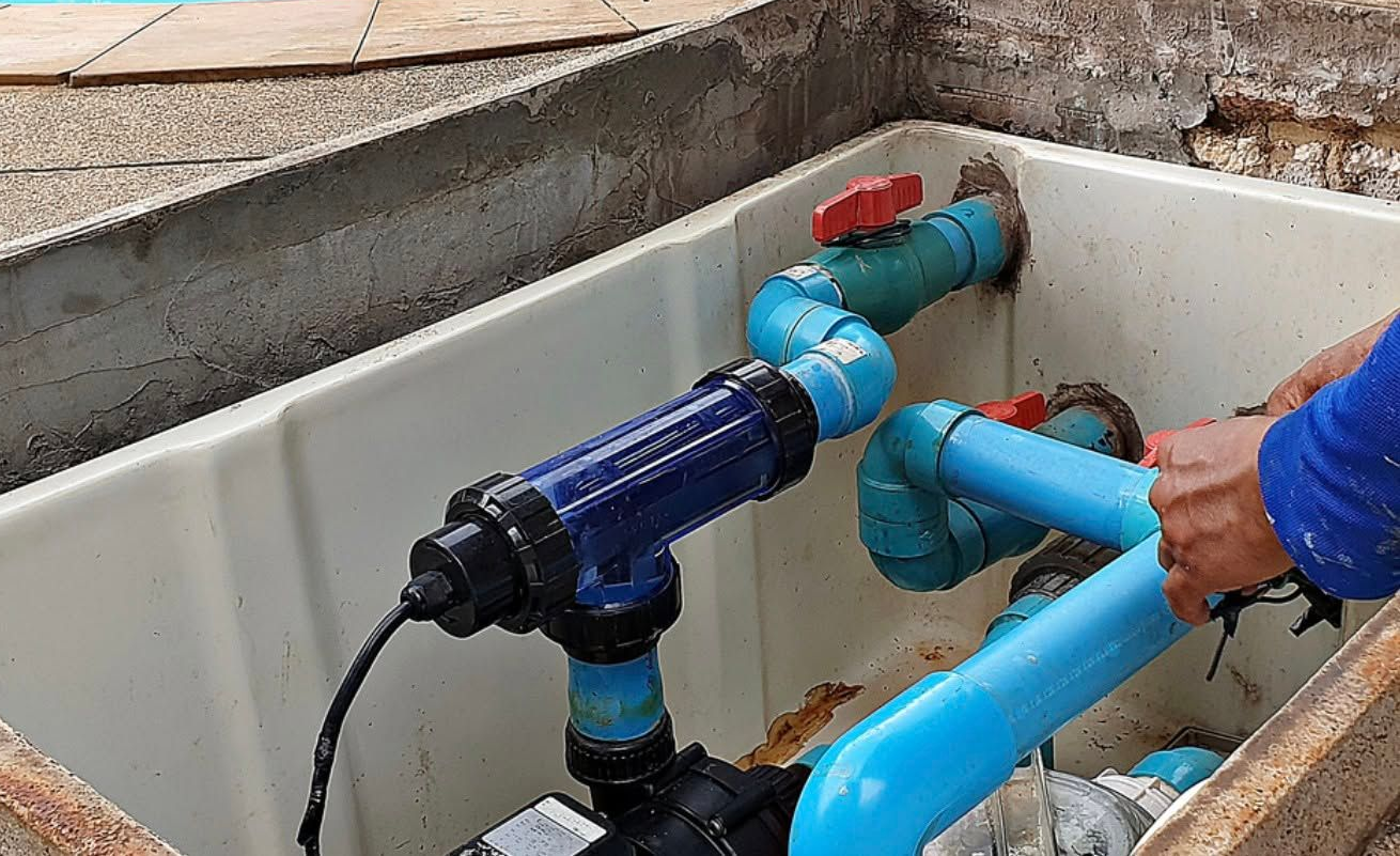 Hand Turning a Blue Valve on Connected Blue and Red Pipes in a Tank — Focus On Water In Cannonvale, QLD