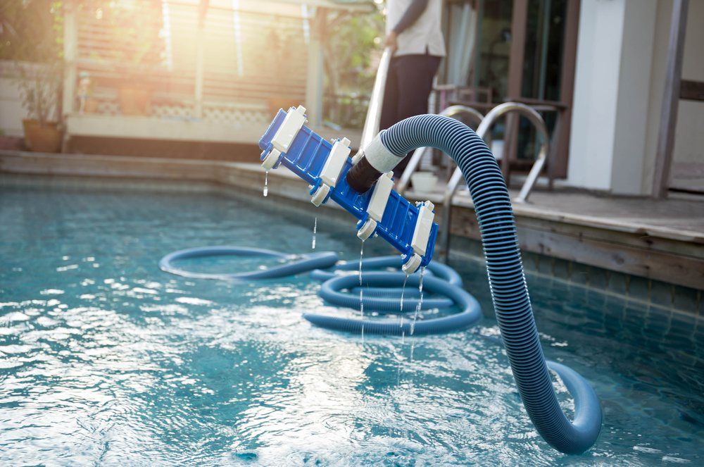 A Man is Cleaning a Swimming Pool With a Vacuum Cleaner —  Focus On Water In Cannonvale, QLD