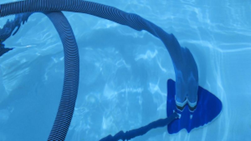 A Vacuum Cleaner is Cleaning the Bottom of a Swimming Pool — Focus On Water In Cannonvale, QLD