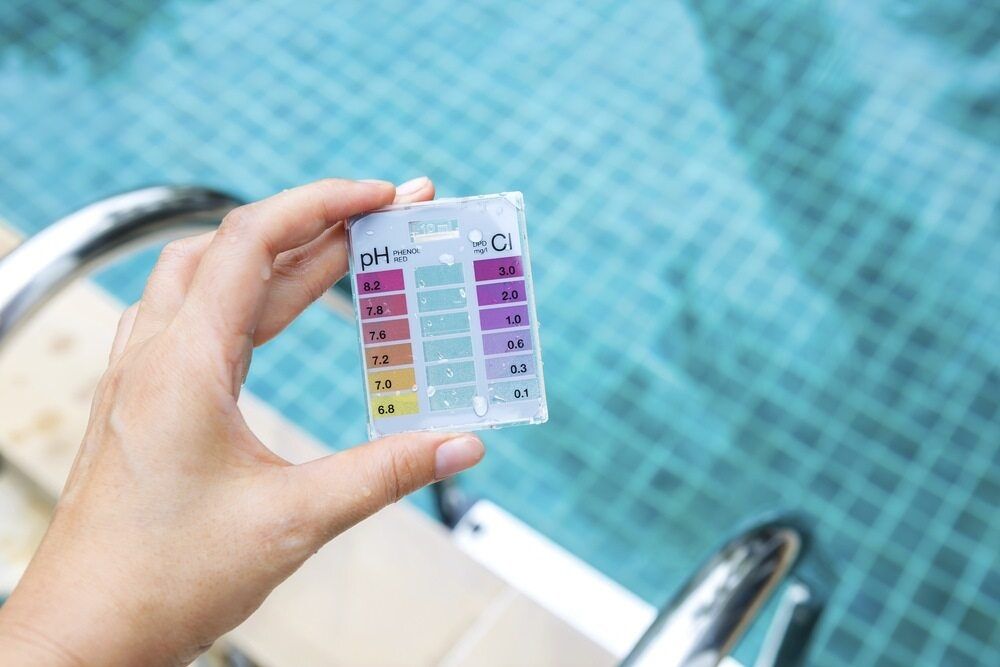 A Person is Holding a Test Kit in Front of a Swimming Pool — Focus On Water In Cannonvale, QLD