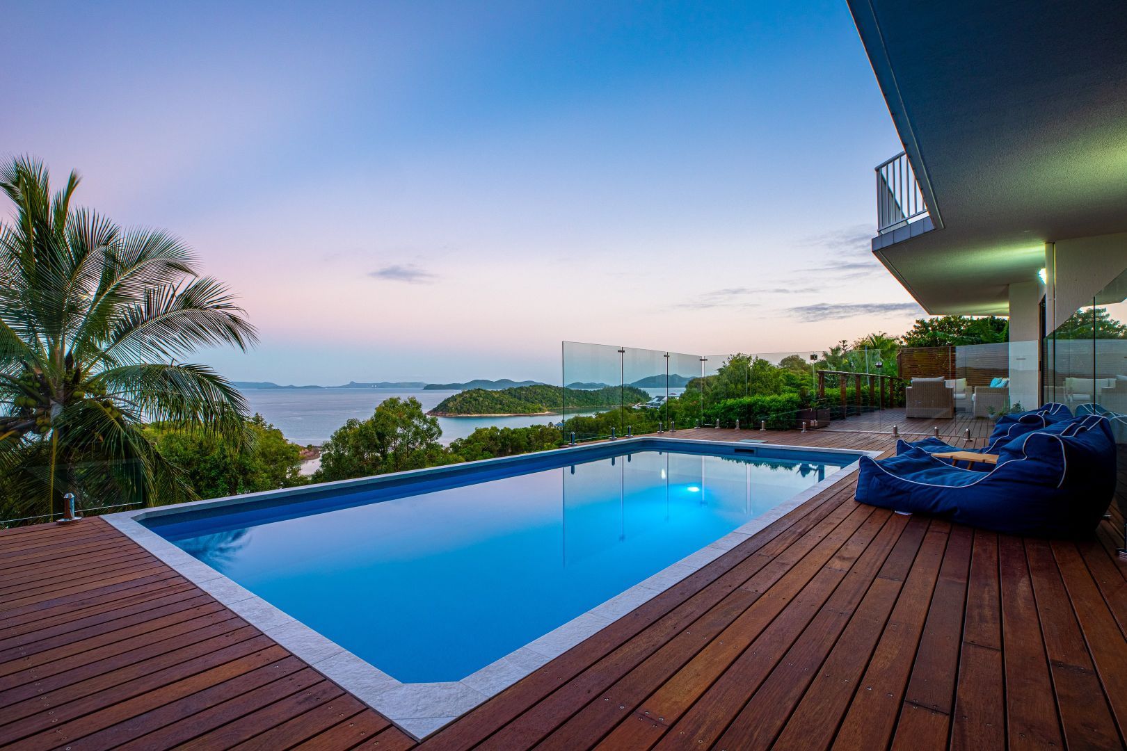 A Large Swimming Pool Surrounded by a Wooden Deck With a View of the Ocean —  Focus On Water In Cannonvale, QLD