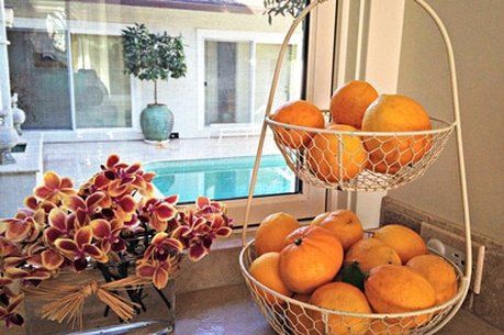 Two baskets of oranges are sitting on a counter next to a window.