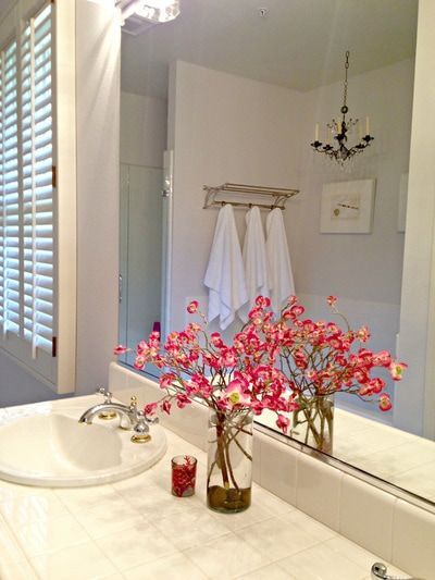 A bathroom sink with a vase of pink flowers on it