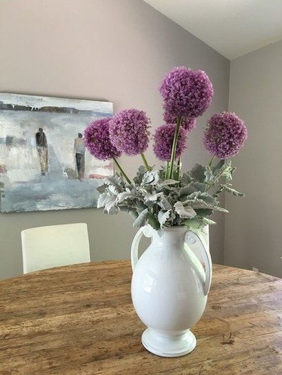A vase filled with purple flowers is sitting on a wooden table.