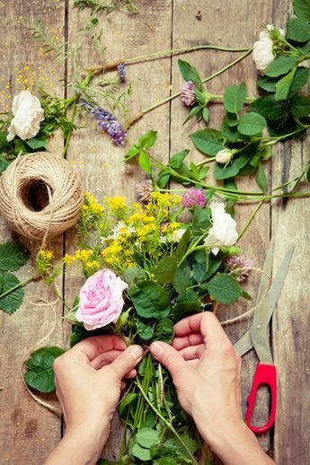 A person is making a bouquet of flowers on a wooden table.