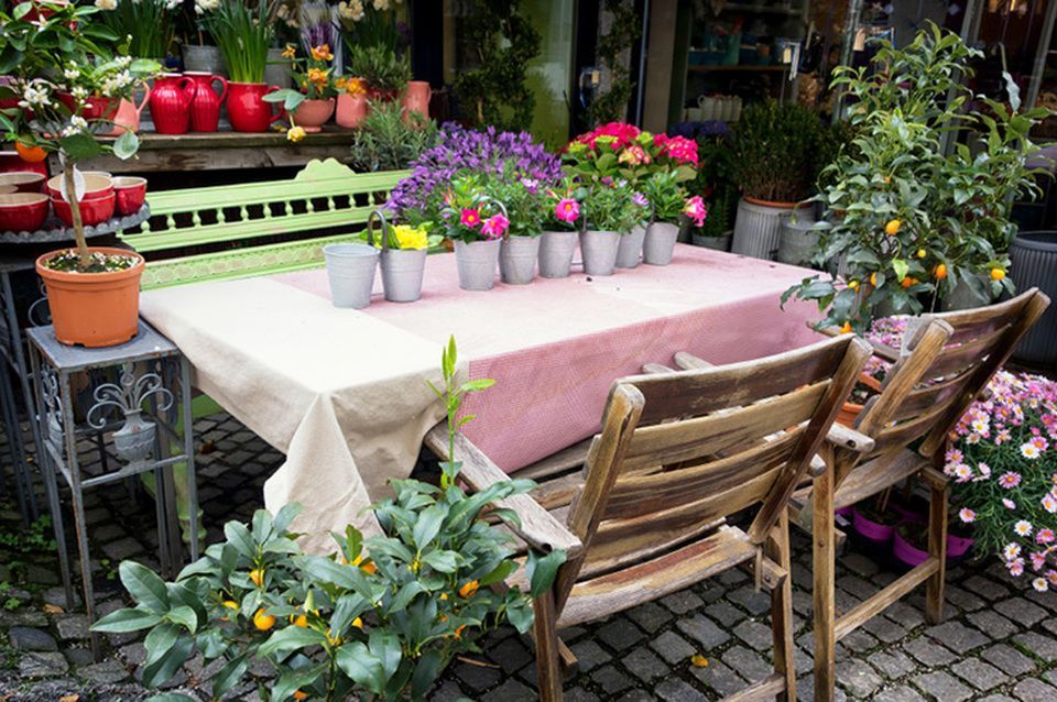 A table with flowers in pots on it in front of a flower shop.