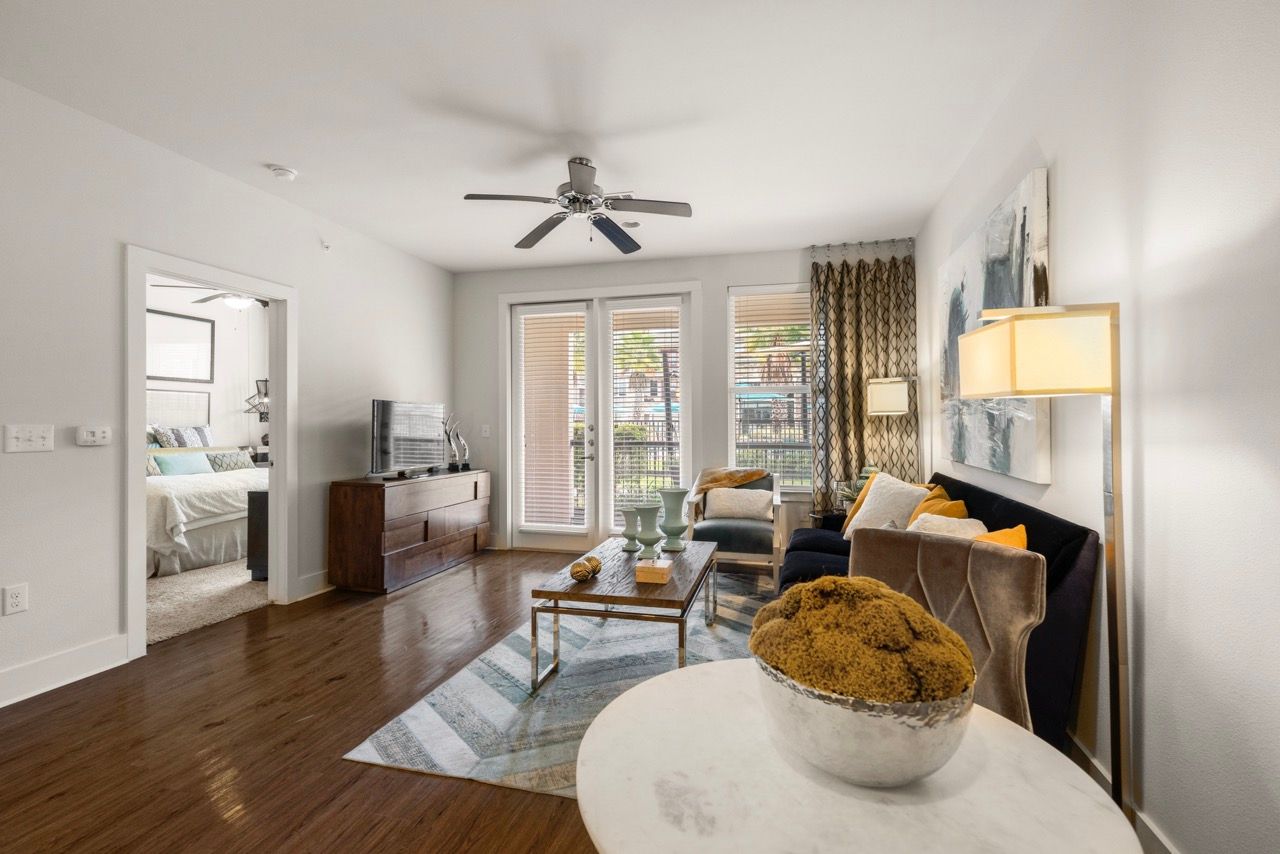 Living room in an apartment with a sofa, coffee table, TV, and French doors to a balcony.