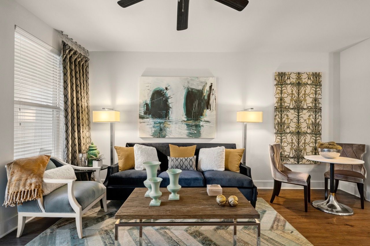 Living room in a modern apartment with a navy sofa, chairs, coffee table, and abstract wall art.