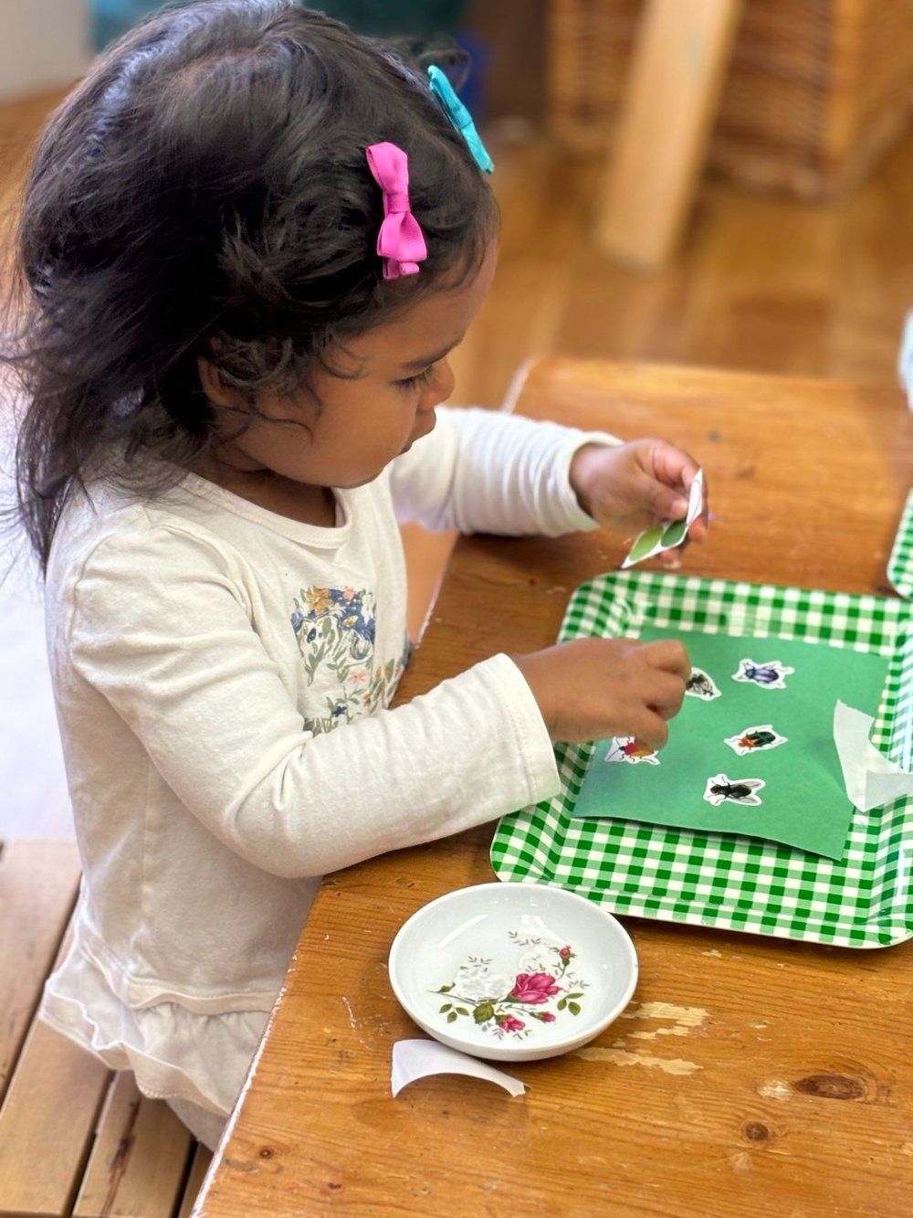 A little girl is sitting at a table playing with stickers.