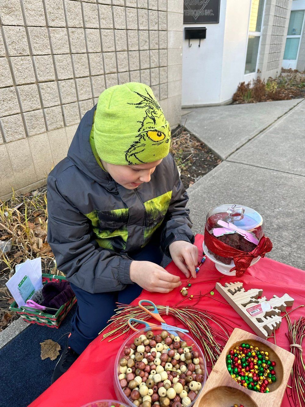 A young boy wearing a grinch hat is sitting at a table with candy.