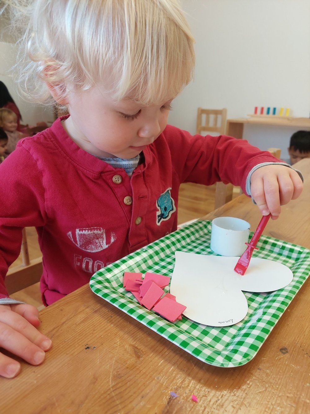 A little girl is painting a heart on a tray