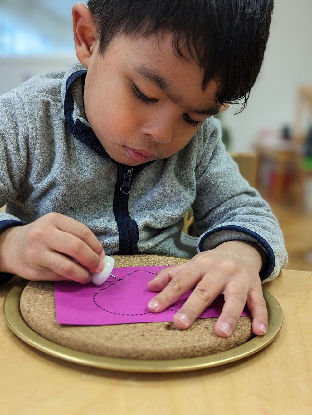 A young boy is playing with a piece of purple paper on a plate.