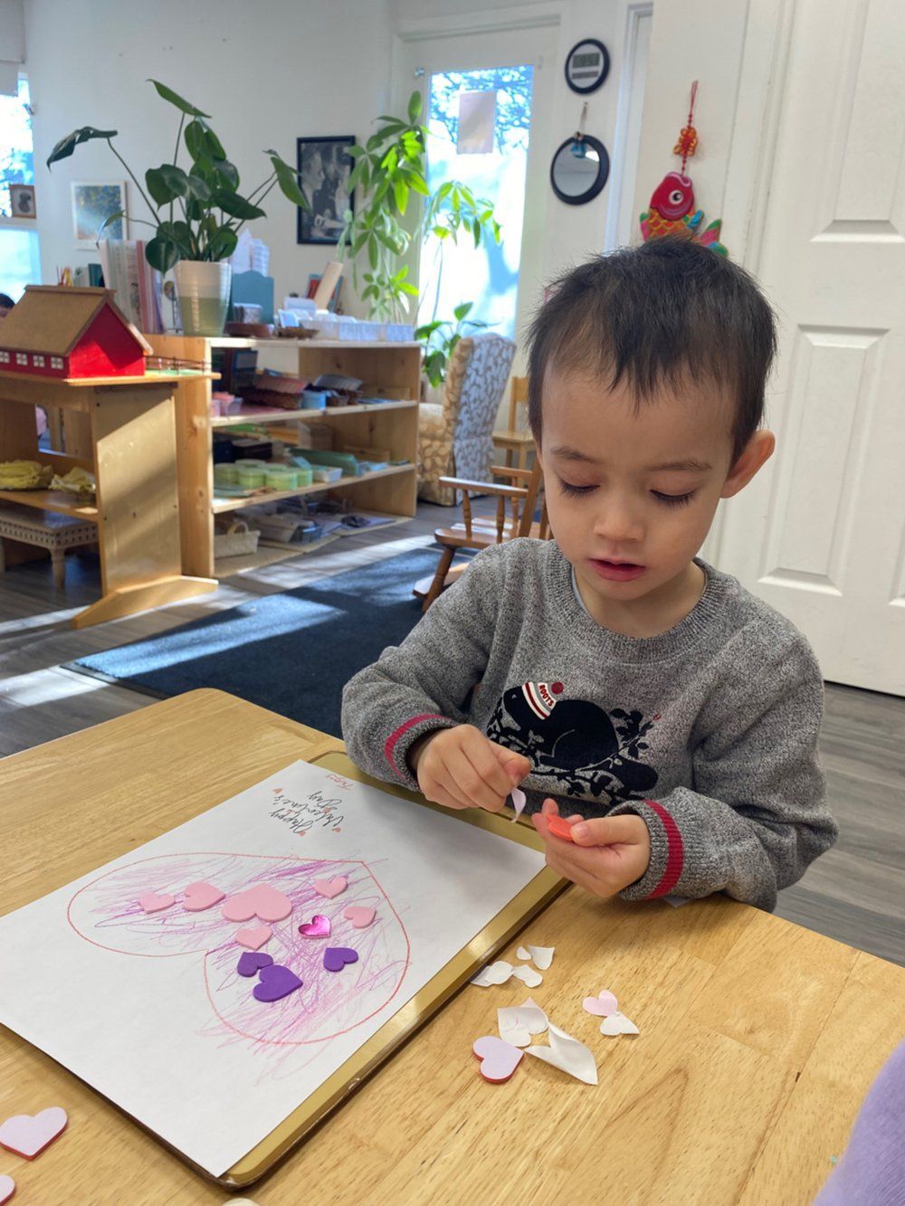 A young boy is sitting at a table with a drawing of a heart on it.
