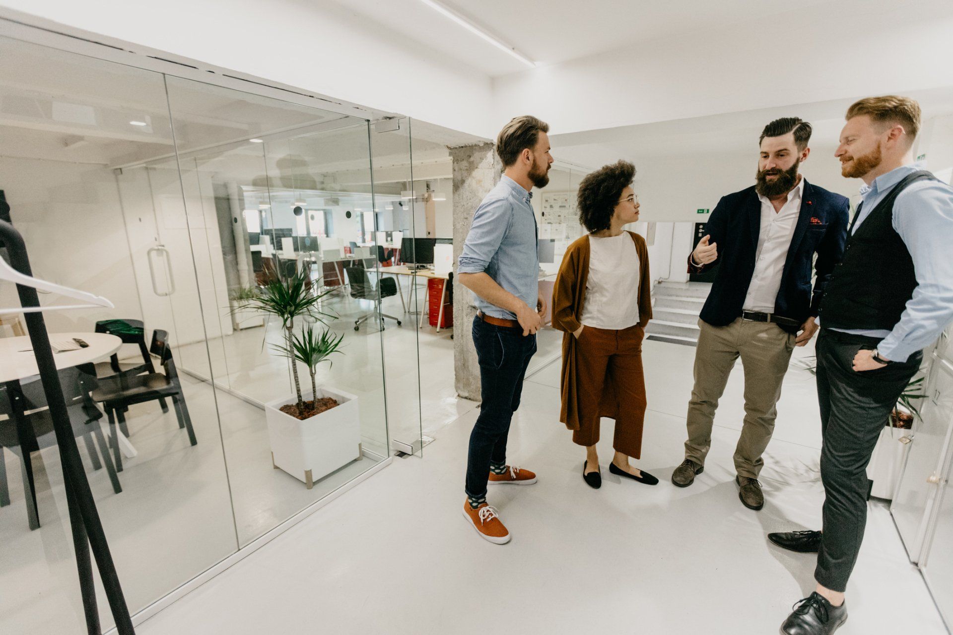A group of people are standing in an office talking to each other.
