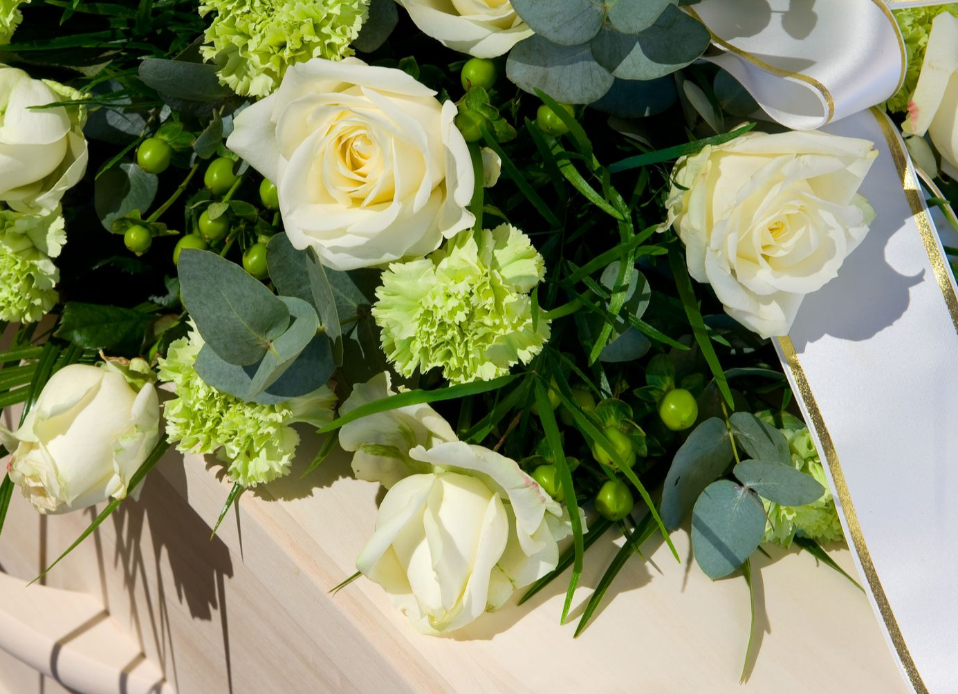 White roses and pale green flowers with eucalyptus arranged in a soft floral bouquet