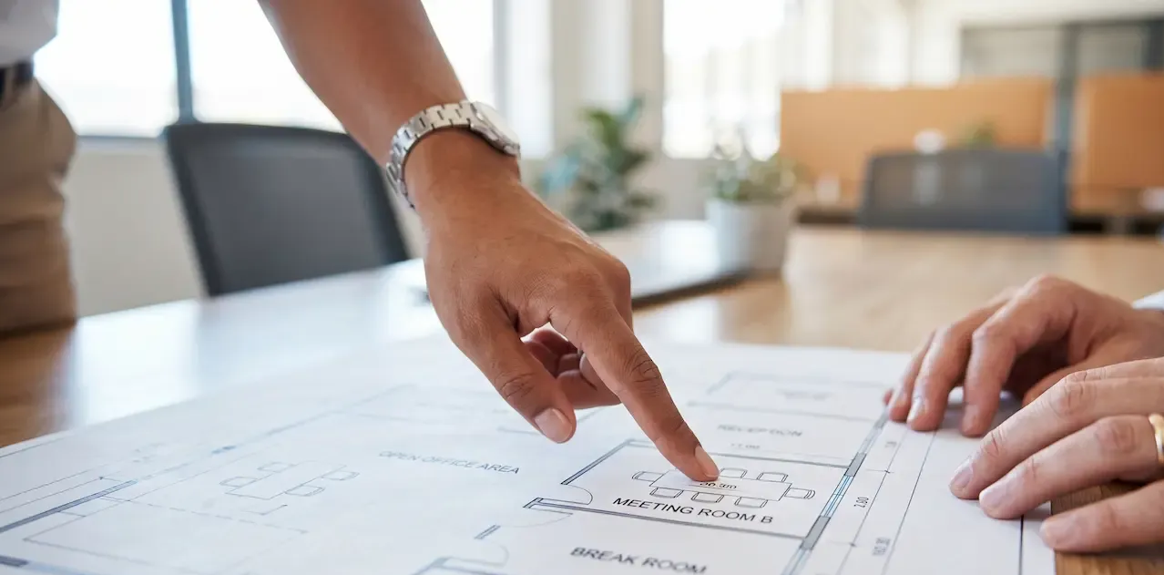 Two hands pointing at a document with charts on a desk in a bright office