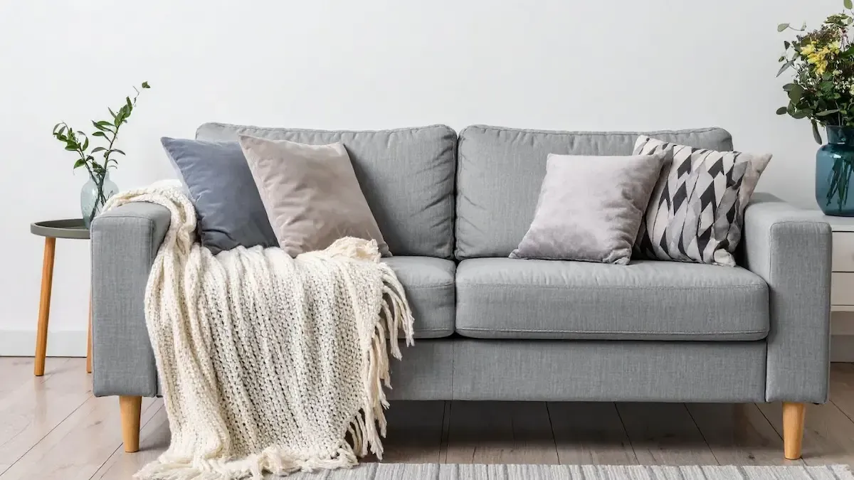 Light gray sofa with pillows and a cream throw blanket in a bright living room