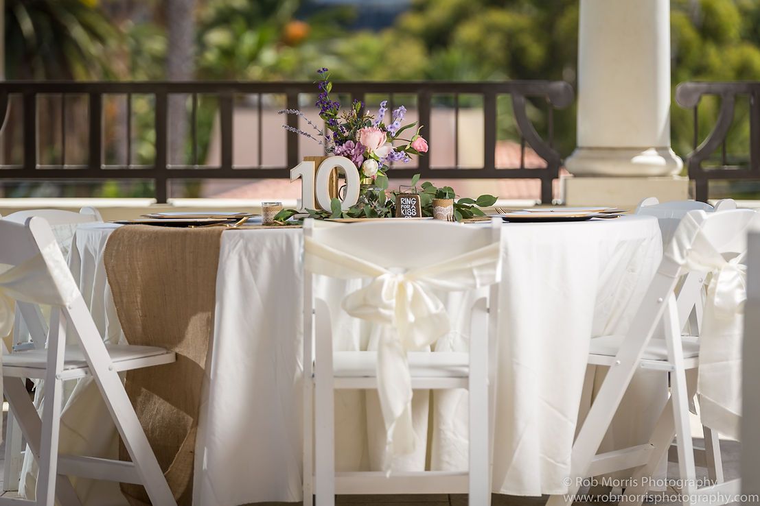 Wedding reception table set with flowers, glassware, and string lights at dusk.