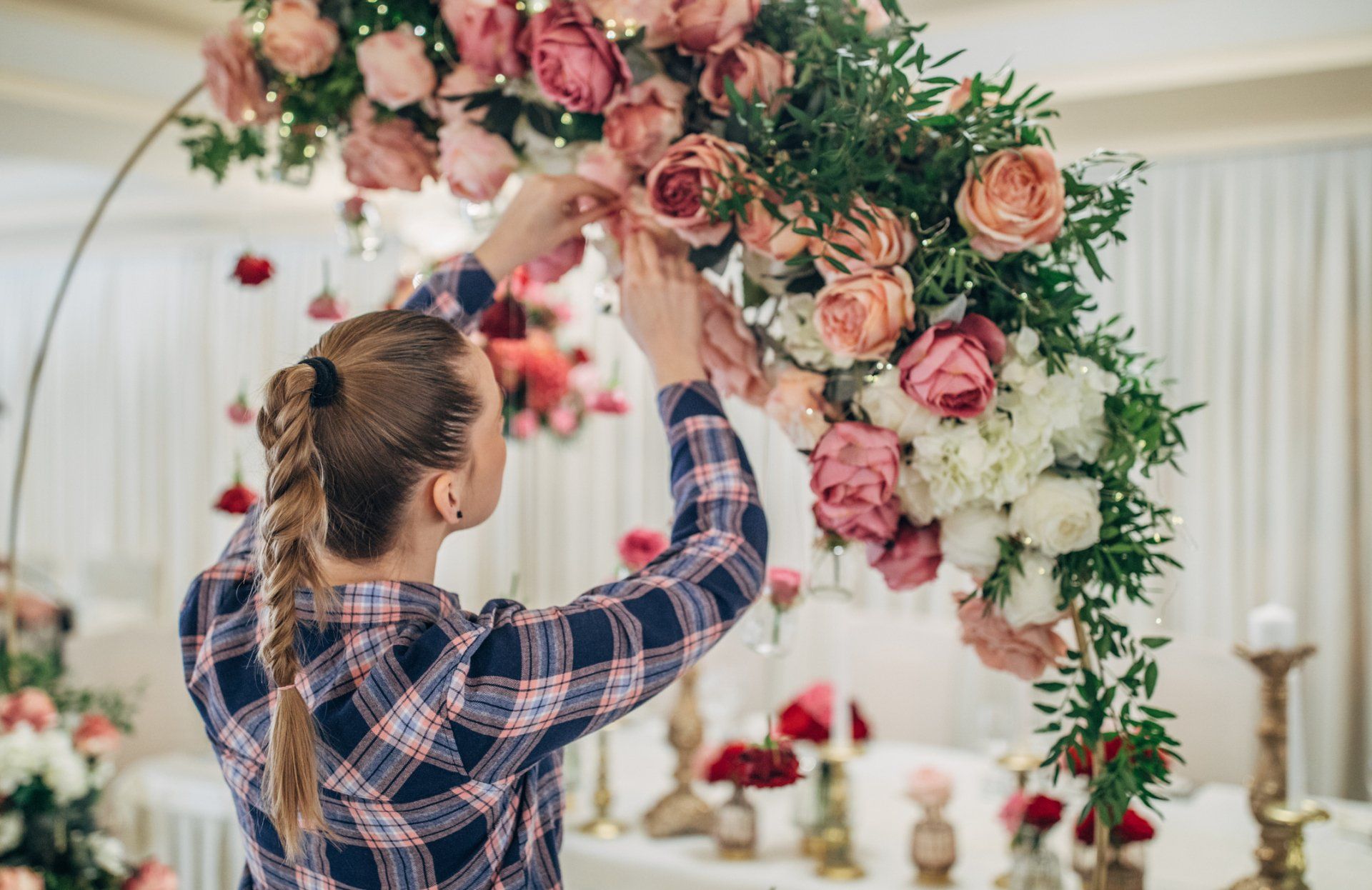 Una persona sistema fiori rosa e bianchi su un arco decorativo all'interno di un edificio.