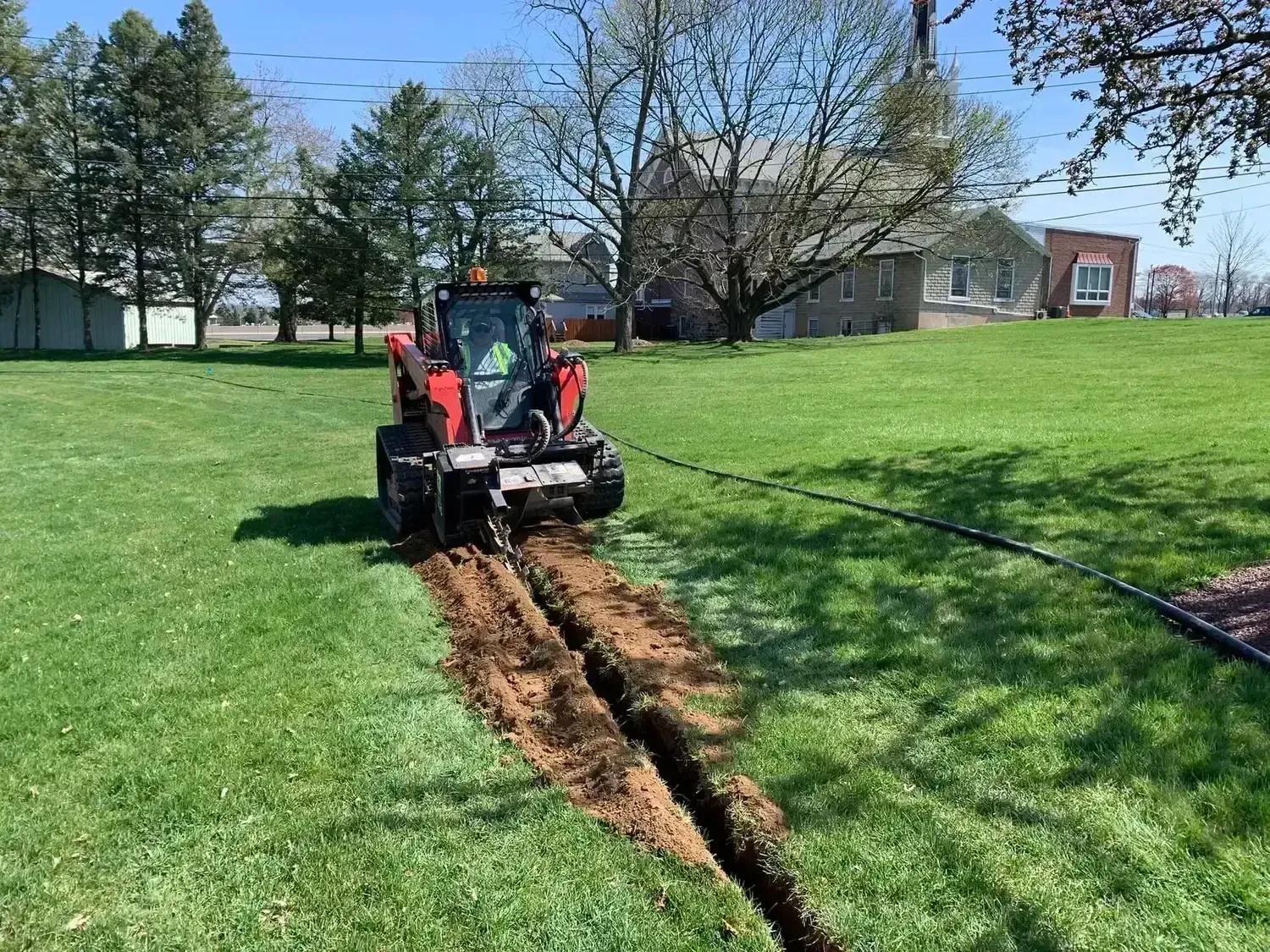 an R&S Property Services worker using a machine to dig a trench on a West Chester, PA Commercial landscape